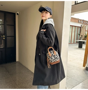 Foto lifestyle di una mini borsa a tracolla in peluche a quadri con nappa e manico