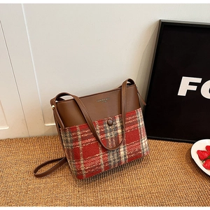 Détail du sac bandoulière en tweed et cuir avec boucle sur tapis de paille