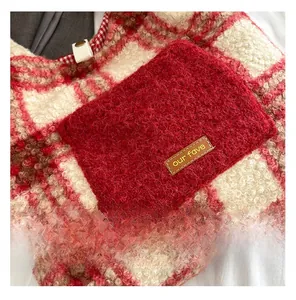 Close-up of red plaid plush tote bag with faux fur pocket and brand label detail