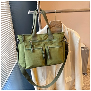 Detail of army green nylon multi-pocket tote bag with woven zippers and crossbody strap