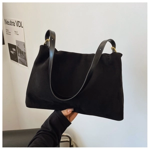 Detailed view of black suede shoulder bag with golden metal buckles and leather straps