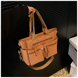 Detail view of large brown multi-pocket tote bag with woven zippers and crossbody strap