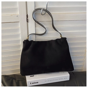 Detail view of the black Boston bag with golden hardware resting on a white book