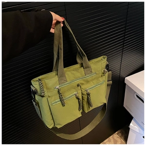 Detail view of military green nylon tote bag with multiple pockets and woven zipper pulls