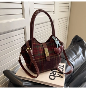 Détail du sac cabas en laine à carreaux rouge et vert avec poignées en cuir marron