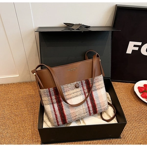 Gros plan d'un sac à bandoulière vintage en cuir et carreaux dans une boîte cadeau