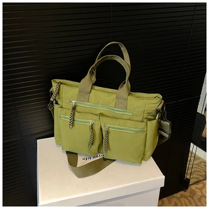 Detailed view of green multi-pocket tote bag with braided zipper pulls and shoulder strap