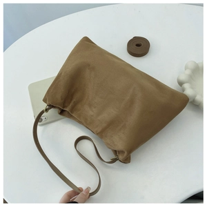 Detailed view of brown suede Boston bag featuring soft folds and durable metal hardware
