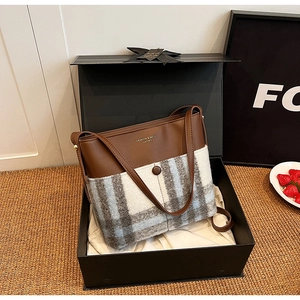 Détail d'un sac cabas vintage en cuir et laine à carreaux dans un élégant coffret cadeau noir