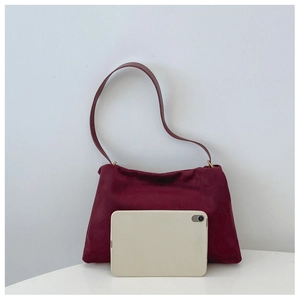 Detailed view of the dark red suede Boston bag showing size reference with a tablet