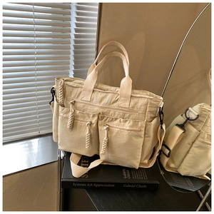 Detailed macro view of beige nylon tote bag featuring multi-pocket design and woven pullers