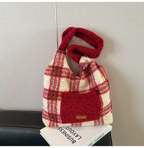 Close-up of red plaid plush tote bag with lambswool texture and 'our fave' patch