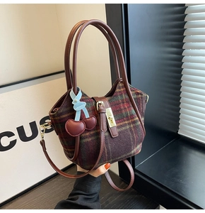 Vue détaillée du sac cabas en laine à carreaux avec poignées cuir et breloque cerise