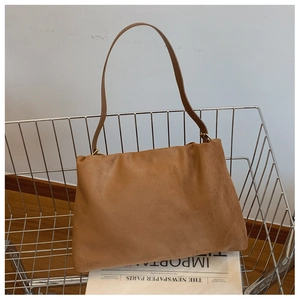 Close-up of brown suede Boston bag in a metal basket with vintage newspaper detail