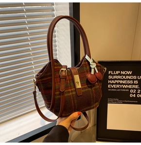 Détail du sac cabas en laine à carreaux avec poignée en cuir et breloque cerise rouge