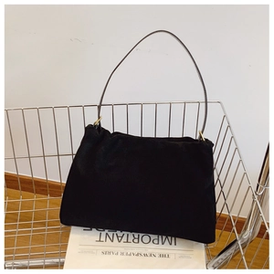 Detail of minimalist black suede Boston bag in a cart with fashion newspaper decor