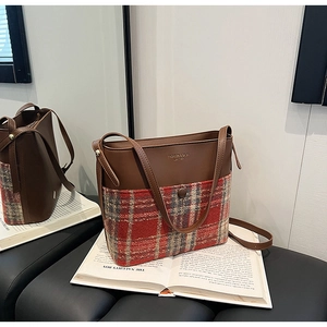 Détail d'un grand sac cabas en cuir marron et tweed à carreaux rouges avec bandoulière