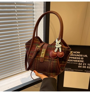 Détail du sac cabas en laine à carreaux avec fermoir doré et breloque cerise