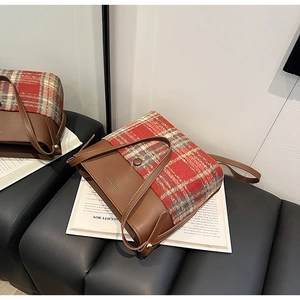 Détail d'un sac cabas vintage en cuir marron et tissu à carreaux rouges avec logo doré