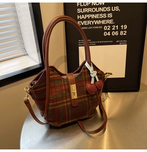 Détail du sac cabas vintage en laine à carreaux avec anses en cuir et breloque cerise