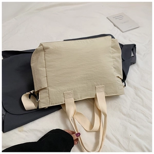 Detail of beige nylon tote bag showing wrinkled texture and durable webbed handle