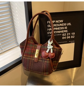 Détail du sac cabas en laine à carreaux rouge et marron avec garniture en cuir chic
