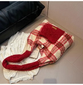 Detailed macro view of plush red plaid tote bag with golden engraved metal plaque