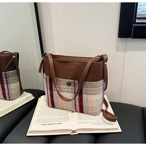 Détail du tissu tissé à carreaux et du cuir marron sur un sac seau à bandoulière élégant
