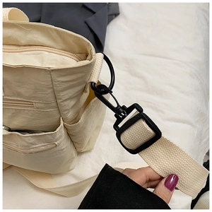 Detail view of the beige nylon tote bag showing the side zipper pocket and shoulder strap