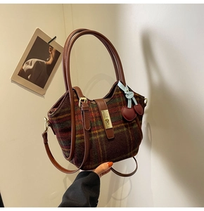 Détail du sac cabas en laine à carreaux avec fermoir doré tournant et breloque cerise
