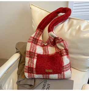 Detail of red and white plaid plush tote bag featuring a solid red front pocket on a sofa