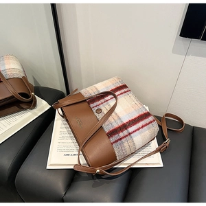Gros plan du sac à bandoulière vintage en cuir marron et tissu écossais avec boucle en métal