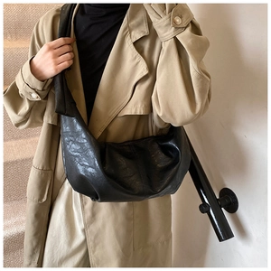 Detail showing the pleated soft leather texture of the black crescent crossbody bag