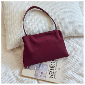 Close-up of a burgundy suede Boston shoulder bag featuring a minimalist vintage design