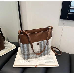 Détail du sac seau vintage en cuir marron et tissu à carreaux gris-bleu élégant