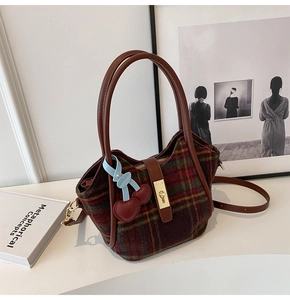 Détail du sac cabas en laine à carreaux vintage avec anses en cuir et breloque cerise
