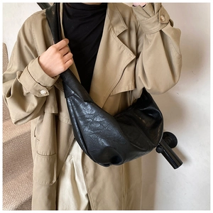 Close-up of black pleated dumpling bag in soft leather with comfortable wide shoulder strap