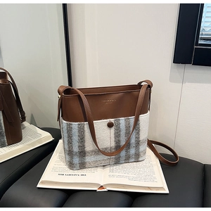 Gros plan du sac seau en cuir et tissu à carreaux sur un livre de style vintage