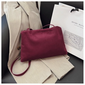 Detail of burgundy suede boston bag styled with a beige blazer and tote bag