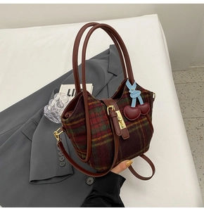 Gros plan du sac fourre-tout en laine écossaise avec lanières en cuir et cerises