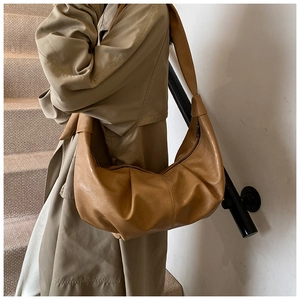 Close-up of a vintage camel-colored pleated dumpling bag with soft leather and wide strap