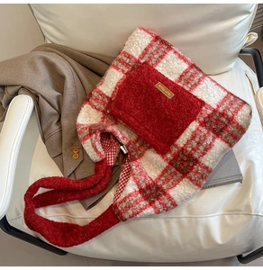 Detail of red and white plaid plush tote bag with furry pocket on white leather chair