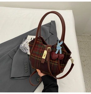 Gros plan du sac cabas à carreaux rétro avec boucle dorée et breloque cerise en cuir