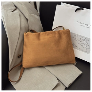 Detail of vintage brown suede Boston bag on blazer with natural light texture