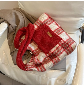 Close-up of plush red plaid tote bag featuring a fuzzy front pocket and soft fuzzy handles