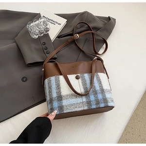 Détail de la texture en cuir marron et laine à carreaux gris sur ce sac à main