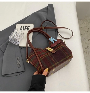 Détail du sac cabas en laine à carreaux avec poignées en cuir et bijou cerise