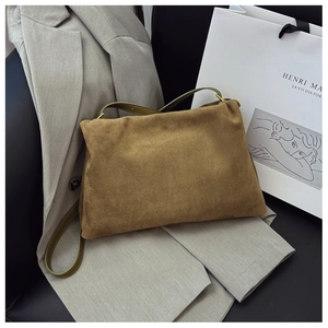 Detail of brown suede Boston bag with green leather shoulder strap on neutral background