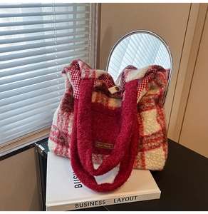 Detailed view of red plaid plush tote bag with leather tag and metallic snap closure