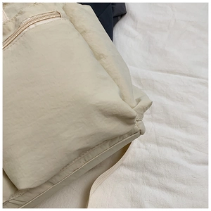Detailed macro view of beige nylon fabric texture and flat stitching on the zipper pocket